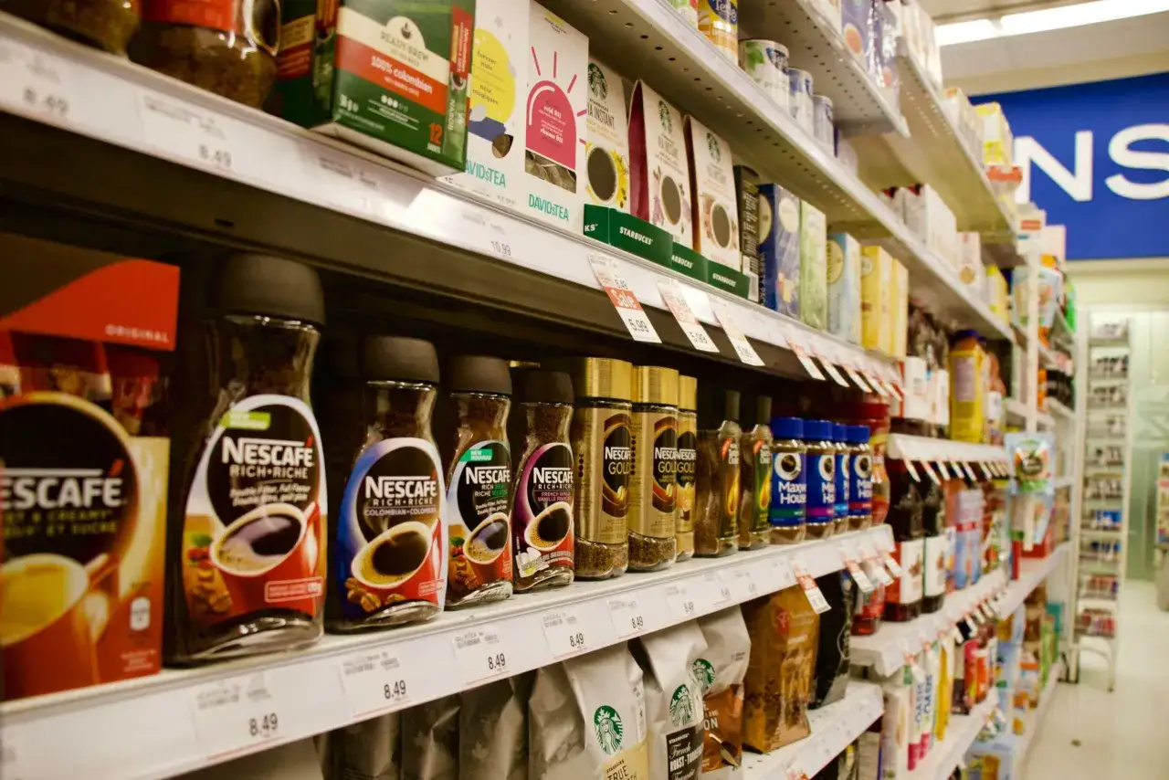 Półki sklepowe z kawą Nescafe i herbatą Davidstea. Widoczne opakowania i ceny, co pokazuje, czym jest trade marketing.