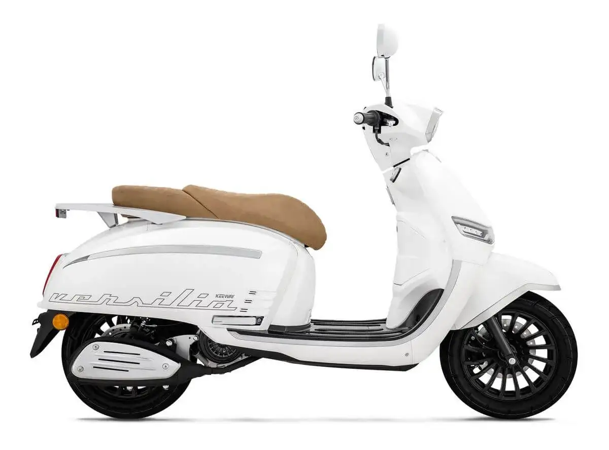 Moto blanca estilo retro, parecida a la Vespa, con asiento marr&oacute;n y detalles plateados.