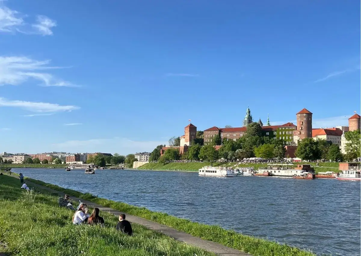 Relaks na trawie nad Wisłą, Wawel w tle. Idealne miejsce na spacer i podziwianie **fajnych miejsc w Krakowie**.