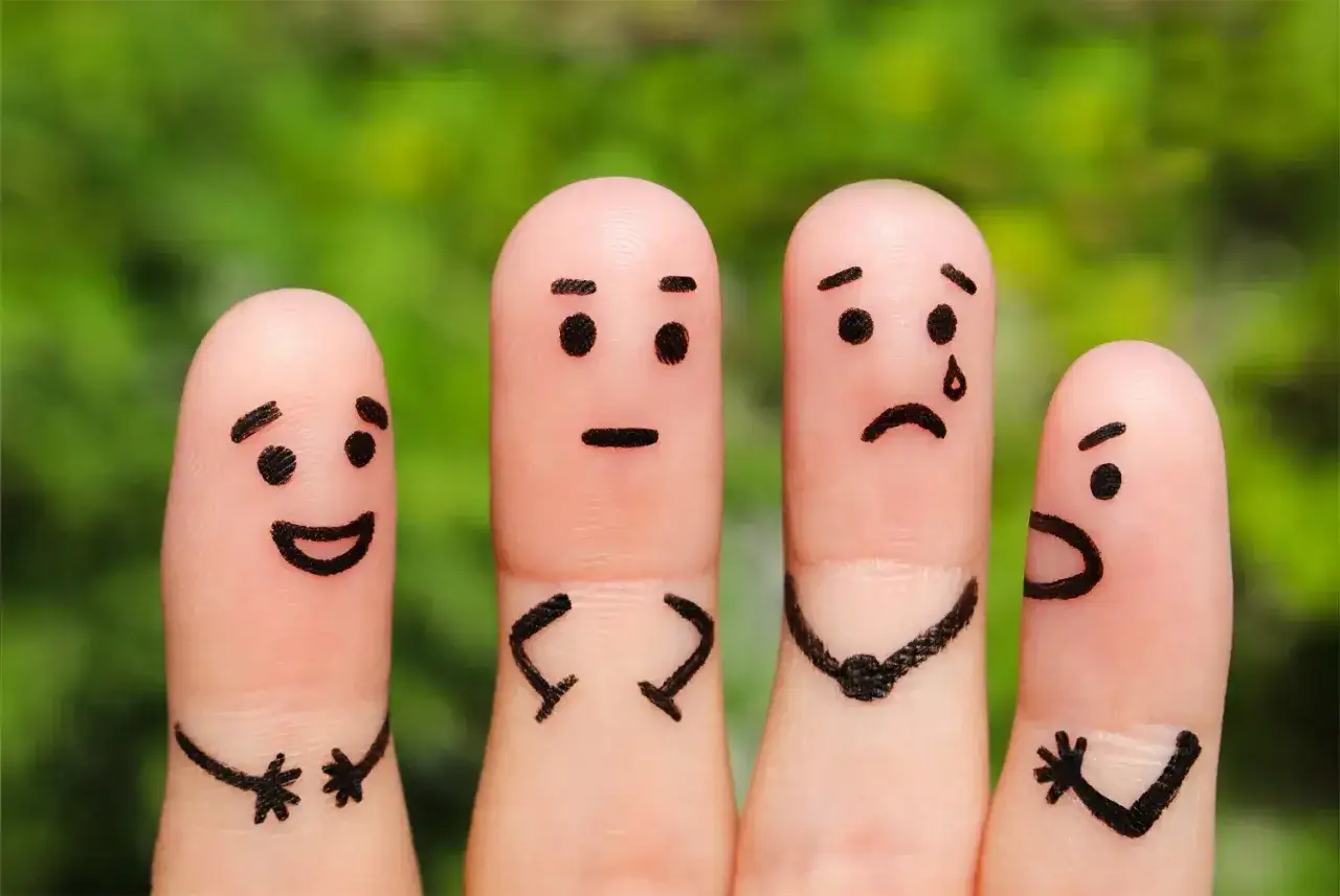Vier Fingerpuppen zeigen verschiedene Emotionen. Ein fröhlicher Finger, ein neutraler, ein weinender und ein wütender. Wichtig für die emotionsregulation kinder.