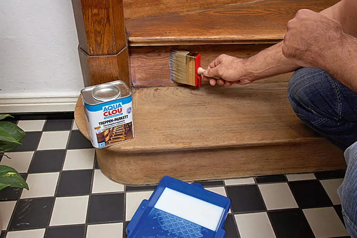 Mann renoviert eine alte Holztreppe mit Lack. Dose 
