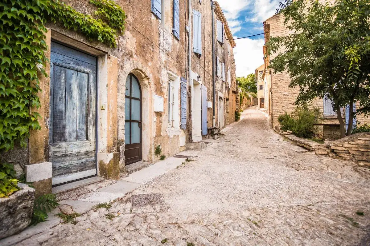 Une ruelle pav&eacute;e serpente &agrave; travers un village perch&eacute;. Des maisons anciennes aux fa&ccedil;ades patin&eacute;es bordent la **route des villages perch&eacute;s**.