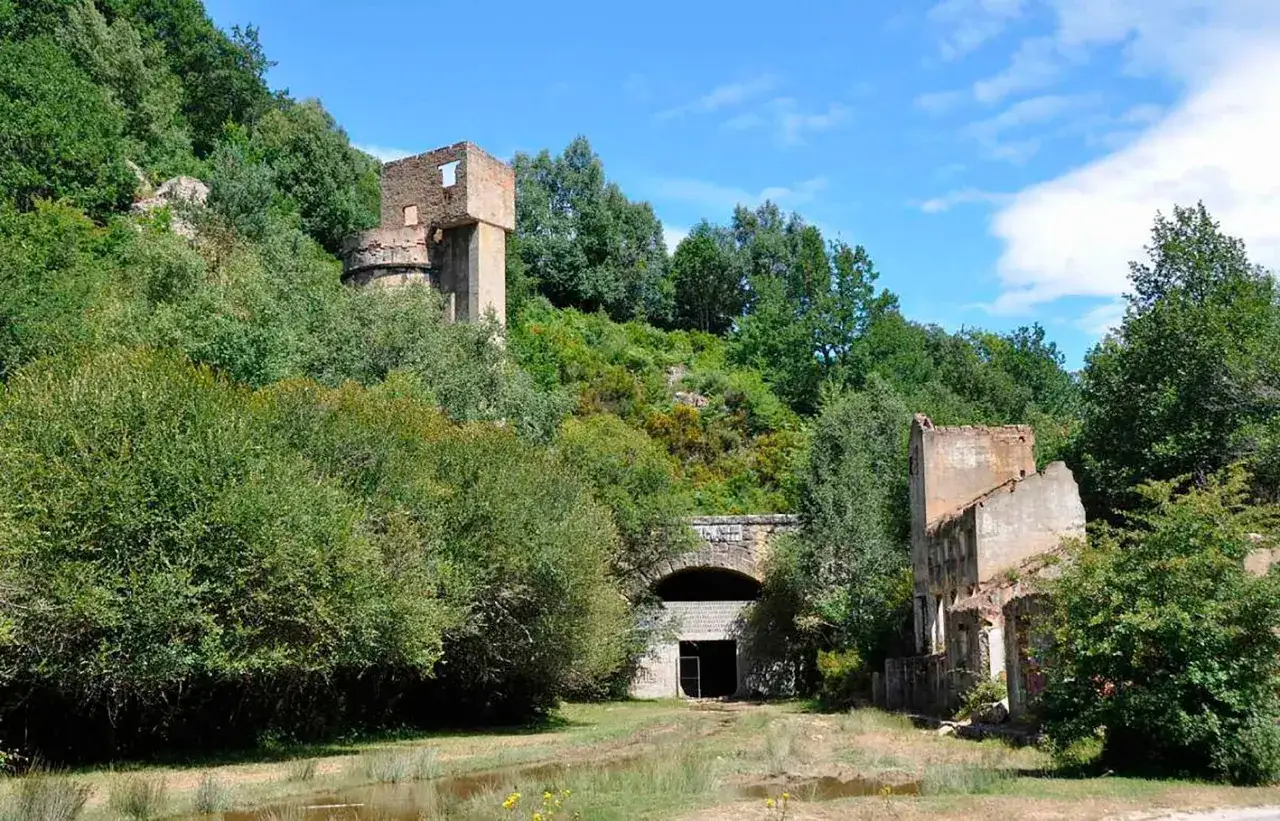 Ruinas de una antigua estación en la vía verde Santander-Mediterráneo, con un túnel y vegetación exuberante.