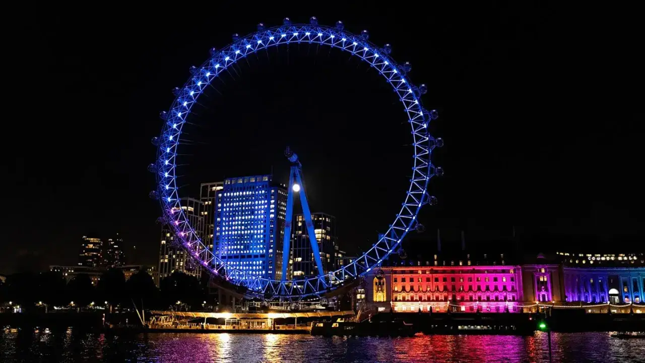 London Eye lyser upp natten i bl&aring;tt och rosa. En vacker vy av Londons klimat, med floden som speglar ljusen.