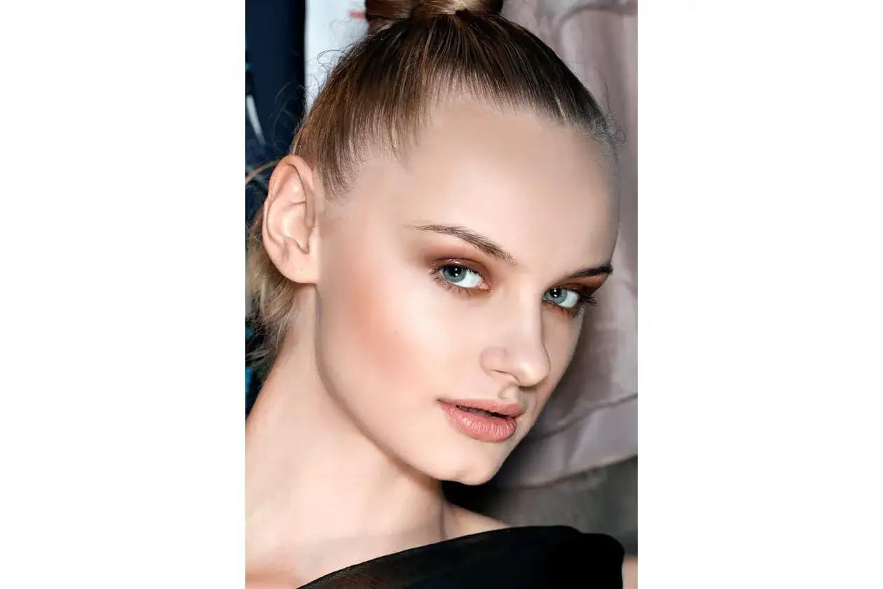 Primo piano di una modella con trucco che evidenzia cos'è il contouring, scolpendo zigomi e mascella per un look definito.