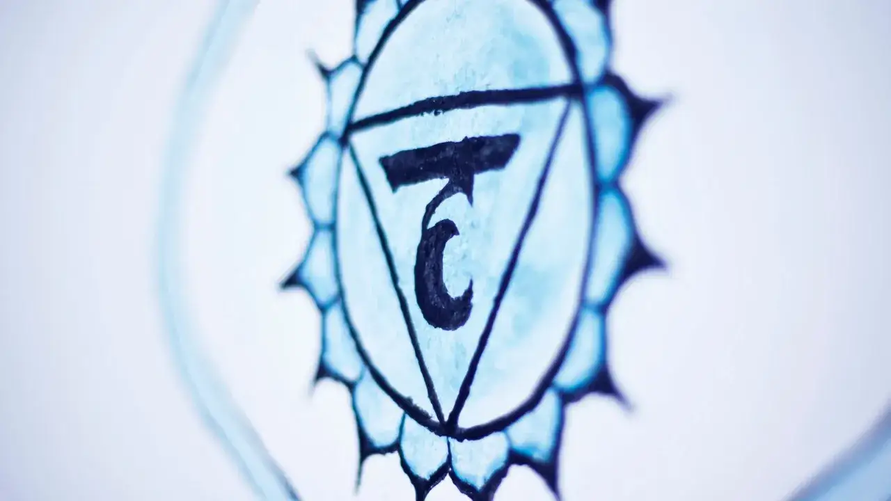 Błękitny symbol z trójkątem i sanskryckim znakiem w środku, reprezentujący czakrę gardła.
