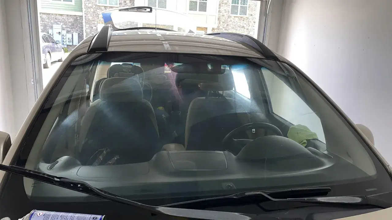 Vue de l'int&eacute;rieur d'une voiture, pr&ecirc;te pour nettoyer pare brise int&eacute;rieur. Si&egrave;ges, volant et si&egrave;ge enfant visibles.