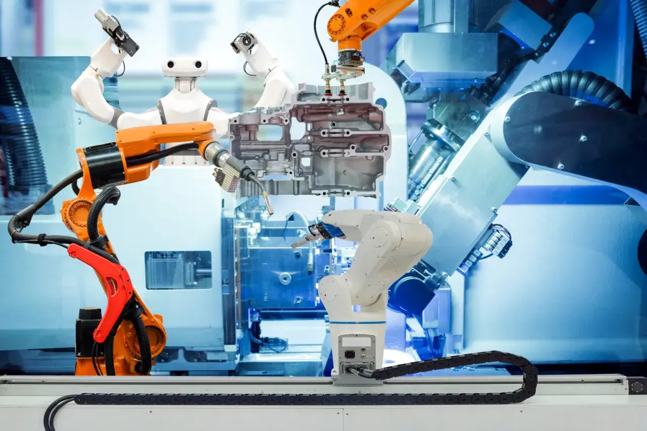 Różne rodzaje robotów przemysłowych pracują nad złożonym elementem silnika.