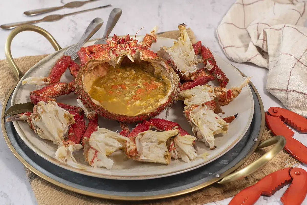 Centollo marisco servido en su caparazón, con patas desprendidas y un caldo sabroso. Ideal para una cena especial.