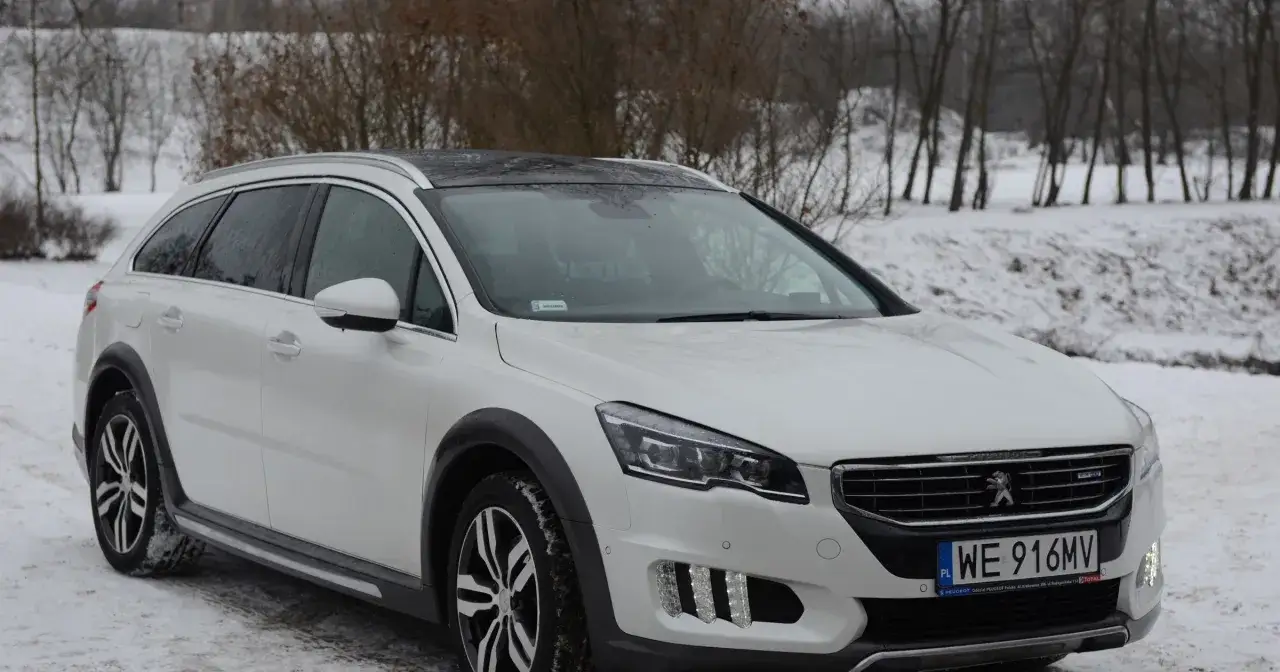 Biały Peugeot 508 RXH na śniegu, z czarnym dachem i felgami. Zbliżenie na przód auta.