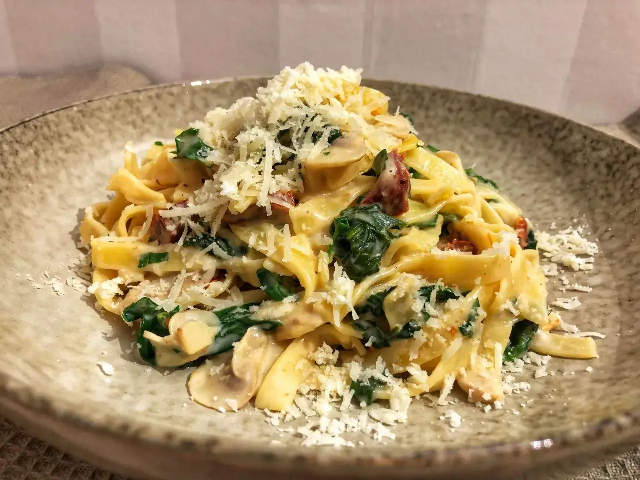En krämig vegetarisk pasta med spenat, svamp och soltorkade tomater, toppad med riven parmesan. En härlig vegetarisk pasta!