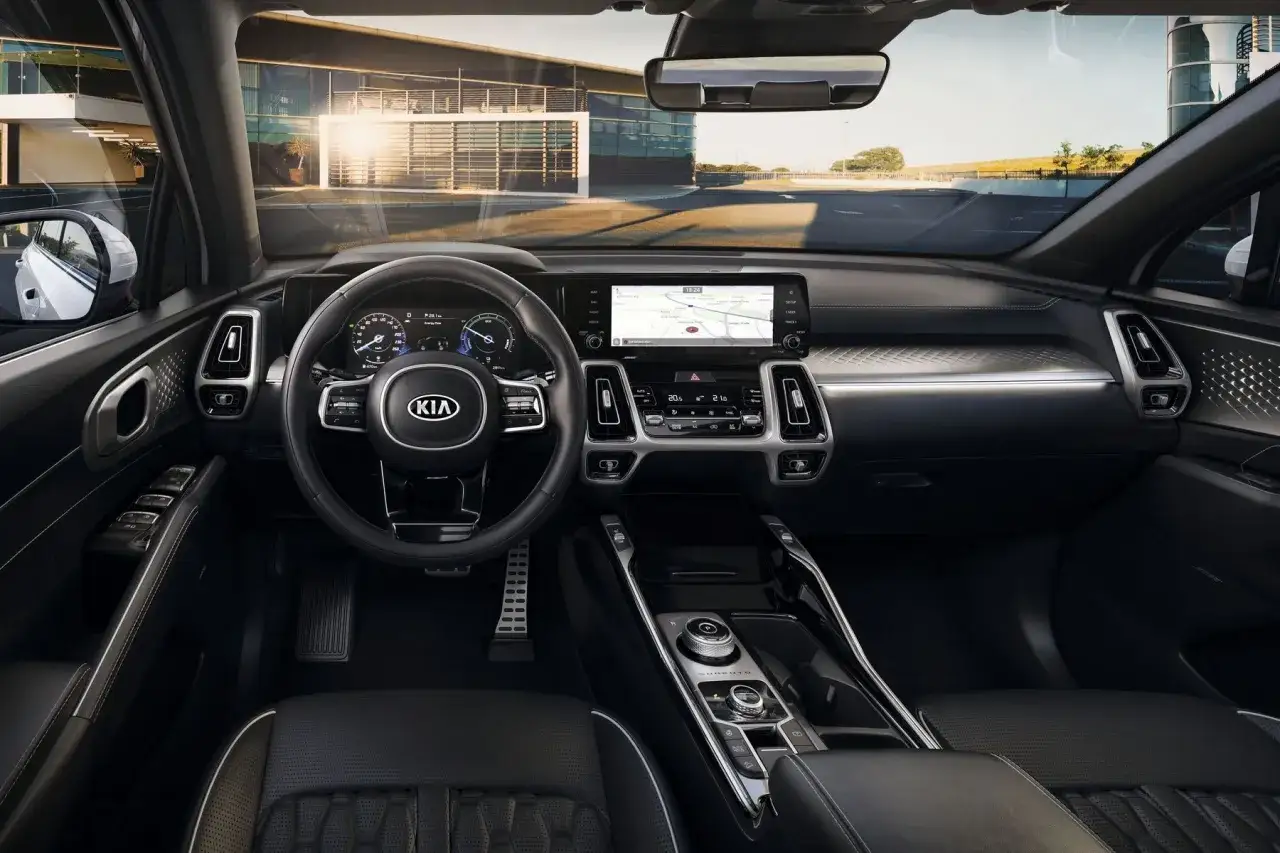 Wnętrze nowej Kia Sorento: nowoczesny kokpit z dużym ekranem multimediów, cyfrowymi zegarami i eleganckimi detalami.