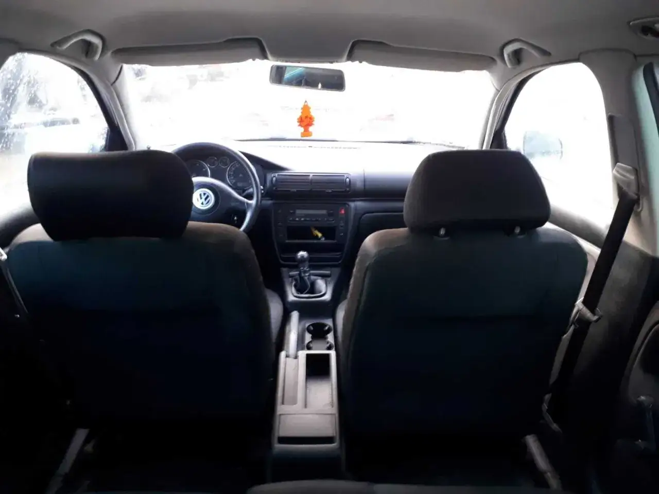 Wnętrze samochodu Volkswagen Passat B5. Widok z tylnego siedzenia na deskę rozdzielczą, kierownicę i fotele.