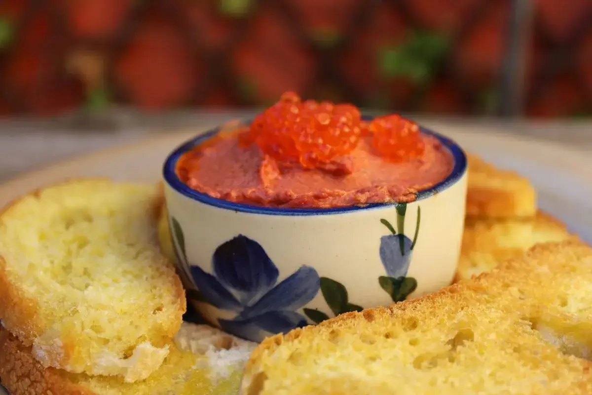 Delicioso paté de higado de rape, coronado con huevas rojas, servido con tostadas crujientes.
