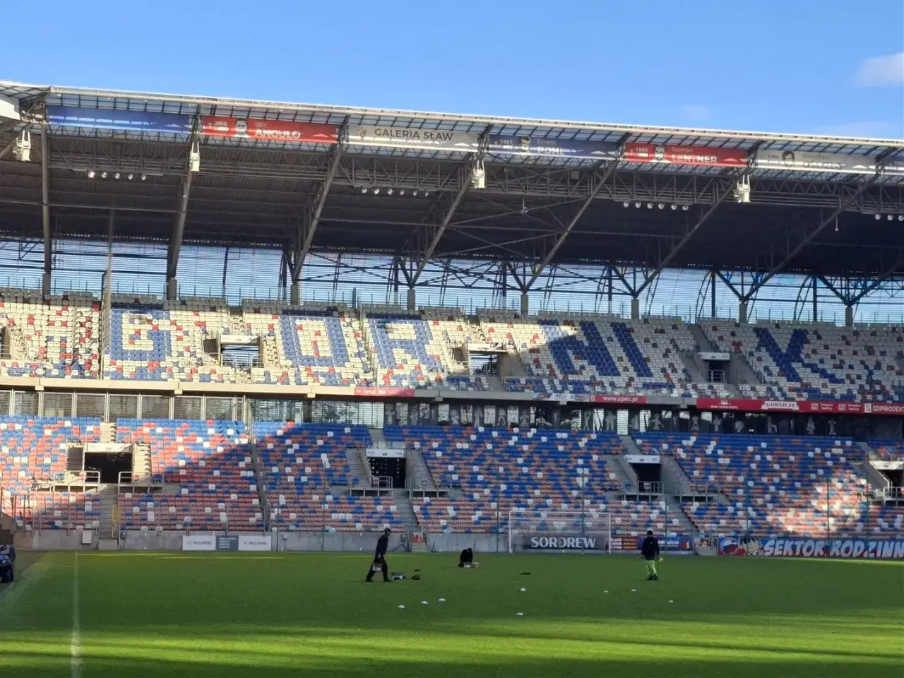 Pusta trybuna stadionu Górnik Zabrze, z widoczną pojemnością stadionu w kolorowych siedzeniach.