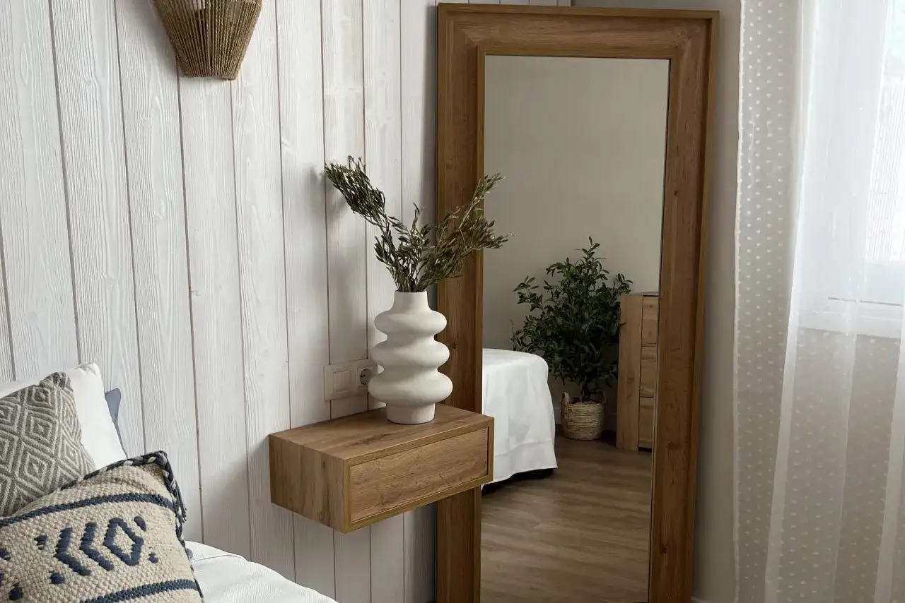 Un tavolino di legno con un vaso bianco e rami secchi, un'idea per come riempire un angolo del salotto.