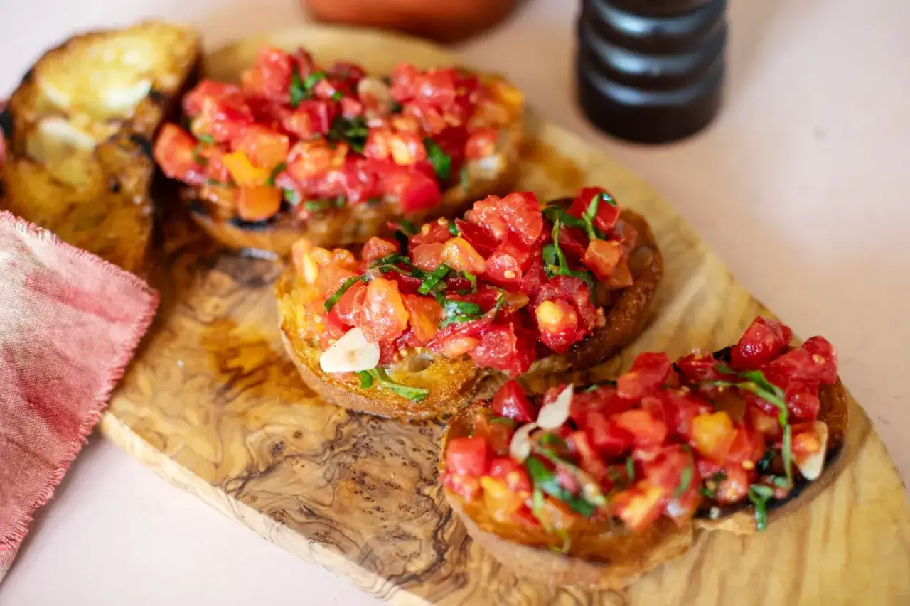 Drei geröstete Brotscheiben mit frischen Tomaten, Basilikum und Knoblauch belegt. Ein köstliches Bruschetta-Rezept, perfekt für den Sommer.