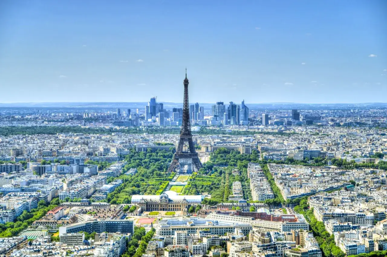 Vue a&eacute;rienne de Paris, la Tour Eiffel se dresse fi&egrave;rement, ses trois &eacute;tages visibles. Au loin, le quartier de La D&eacute;fense.