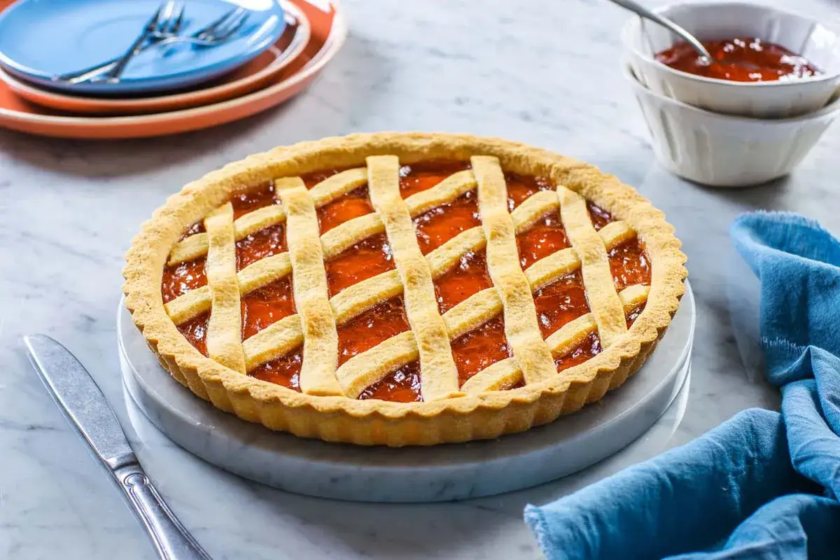 Deliziosa crostata di marmellata con una griglia dorata di pasta frolla, pronta per essere gustata.