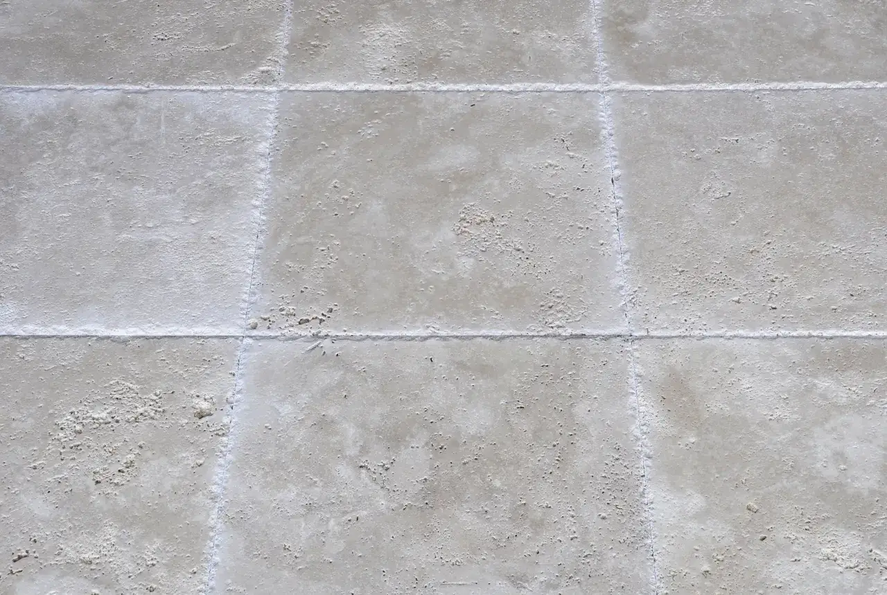 Gros plan sur des dalles de pierre beige avec un joint carrelage ext&eacute;rieur blanc et net, pr&ecirc;t pour une terrasse durable.