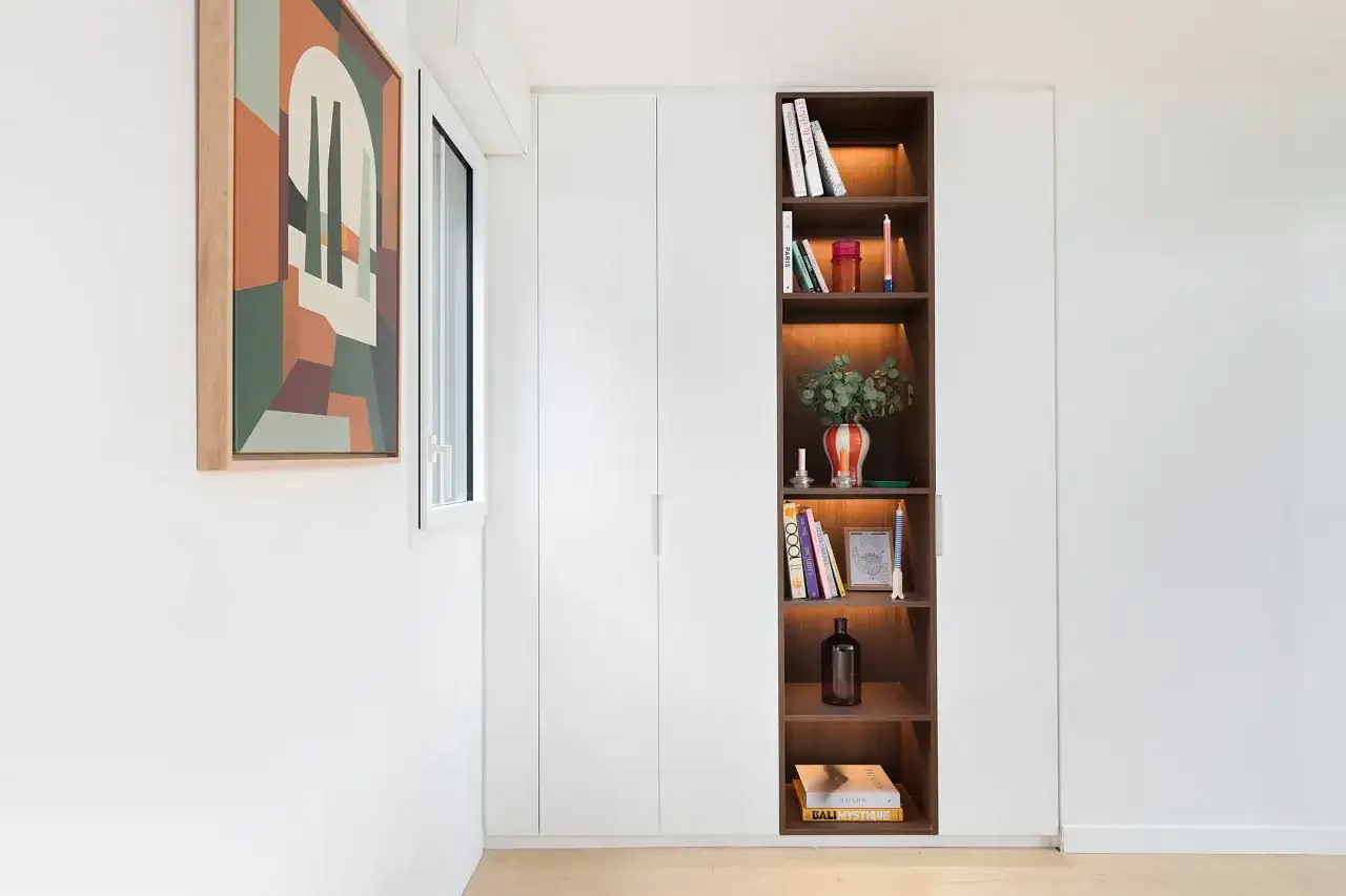 Id&eacute;es pour comment am&eacute;nager un placard int&eacute;gr&eacute; : une niche ouverte avec &eacute;tag&egrave;res en bois sombre, &eacute;clair&eacute;es, pr&eacute;sente des livres et des objets d&eacute;coratifs.