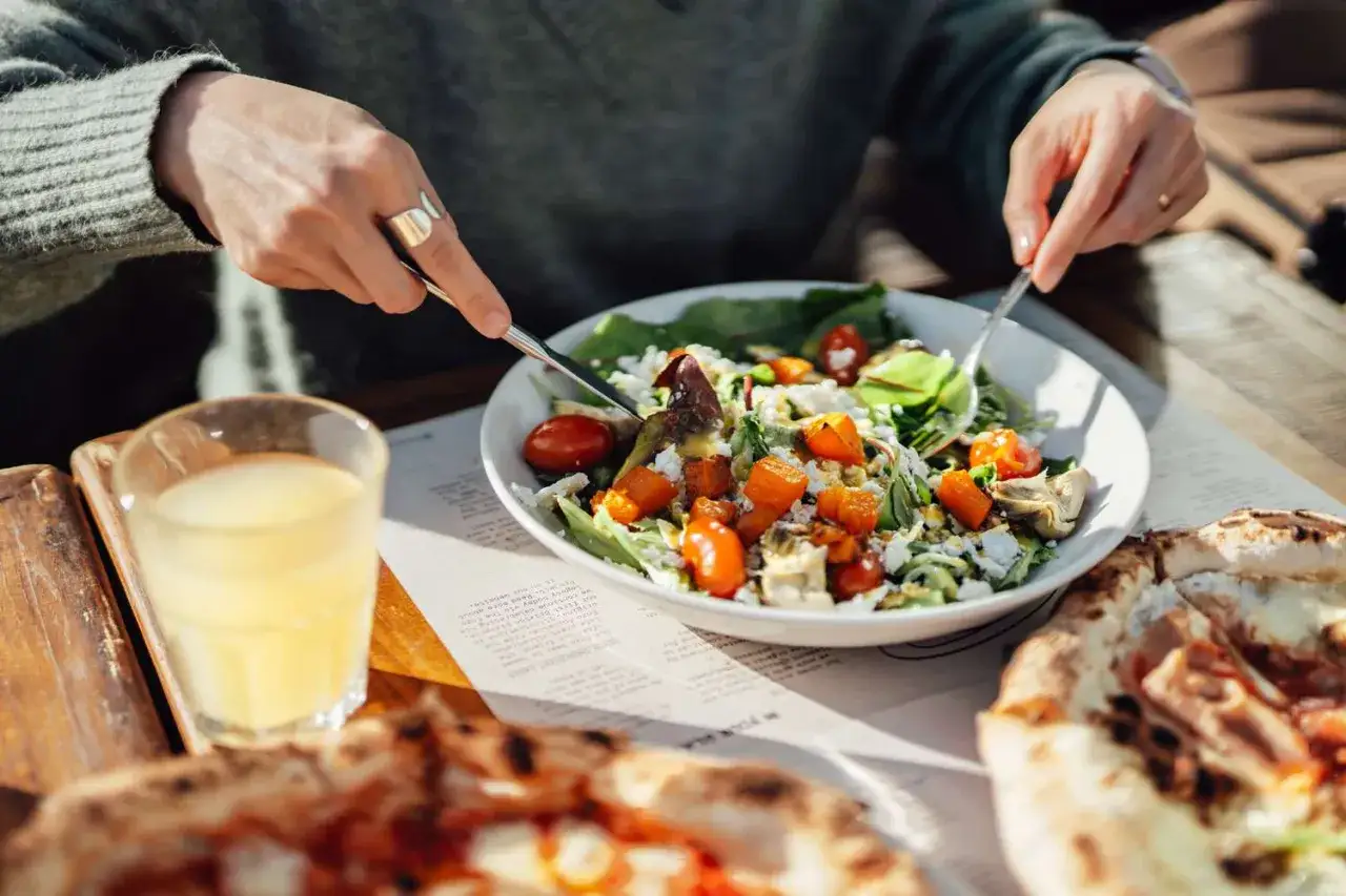 Po 16 godzinach głod&oacute;wki, pyszna sałatka z dynią i fetą smakuje wybornie. Obok pizza i sok.