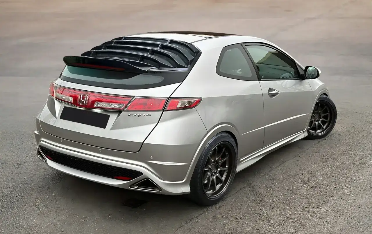 Srebrny Honda Civic VIII z przyciemnianymi szybami i sportowym spoilerem na klapie bagażnika.