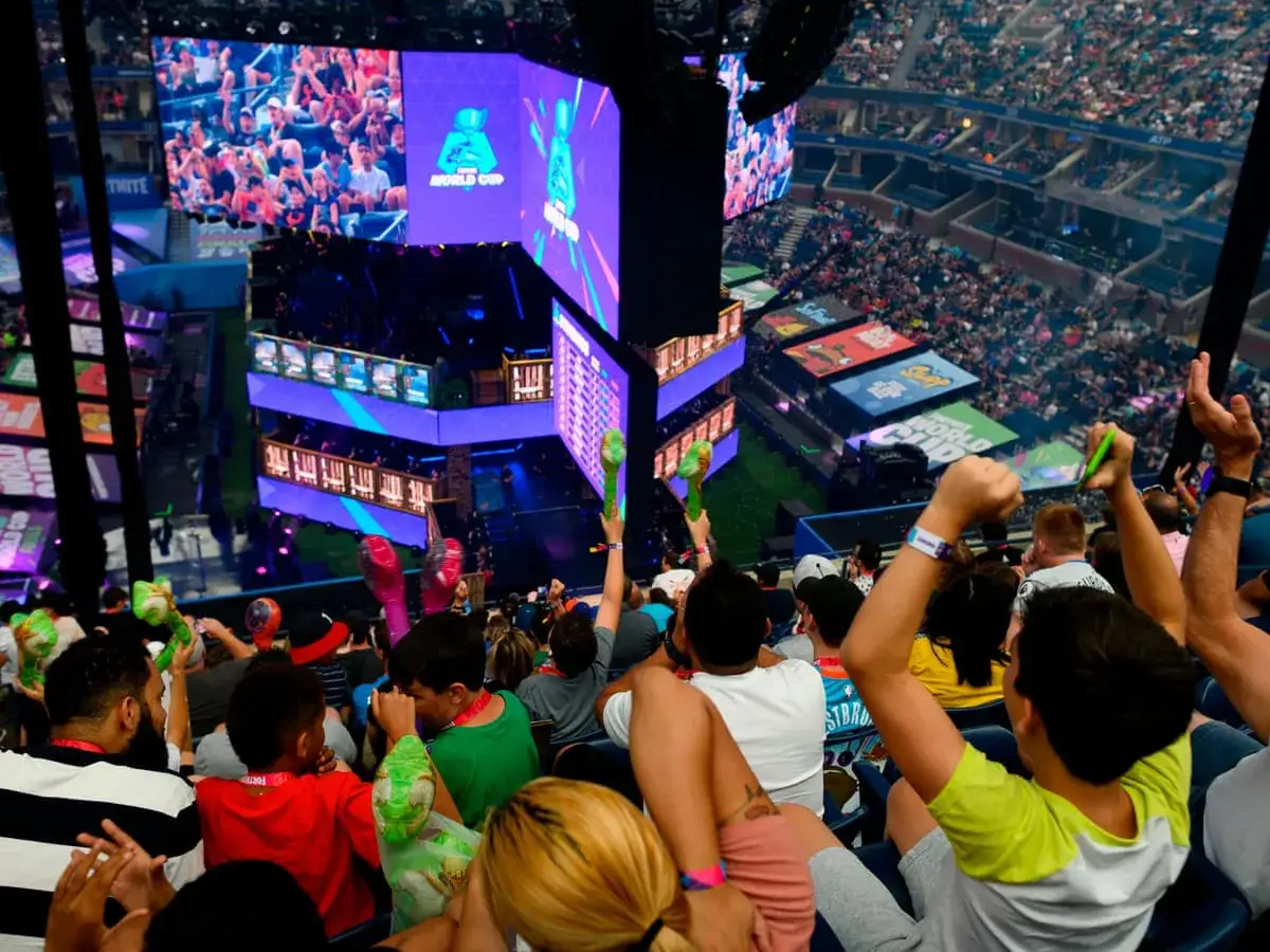 Widownia kibicuje podczas wielkiego turnieju Fortnite. Tłum w stadionie, ekrany z rozgrywką, gracze na scenie.