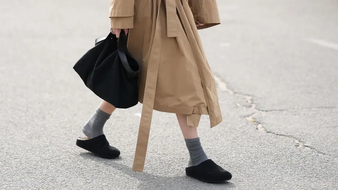 Persona camina con zuecos negros y calcetines grises, mostrando cómo llevar zuecos con calcetines para un look casual y cómodo.