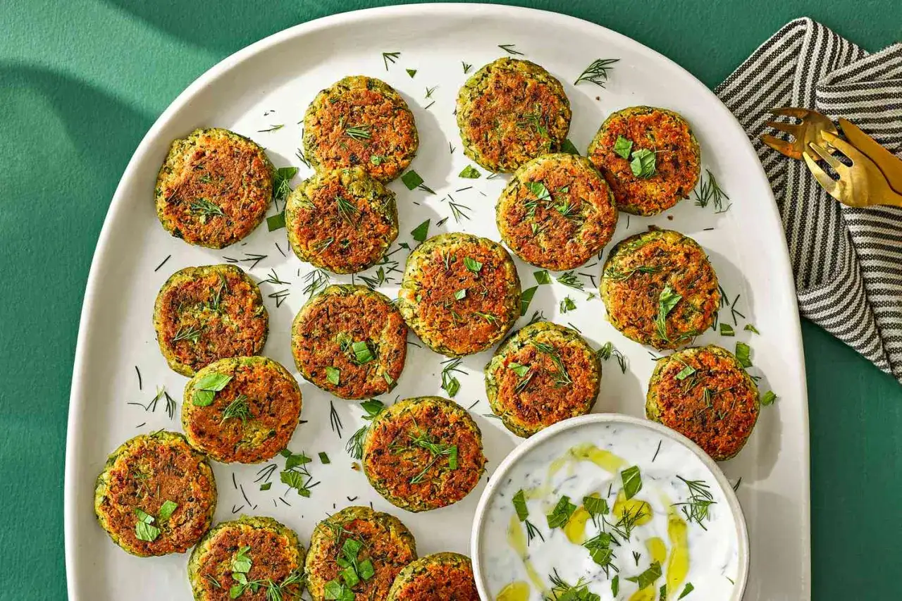 Frisch zubereitete Falafel, perfekt zum **falafel selber machen**. Serviert auf einer Platte mit Kr&auml;utern und einem Dip.