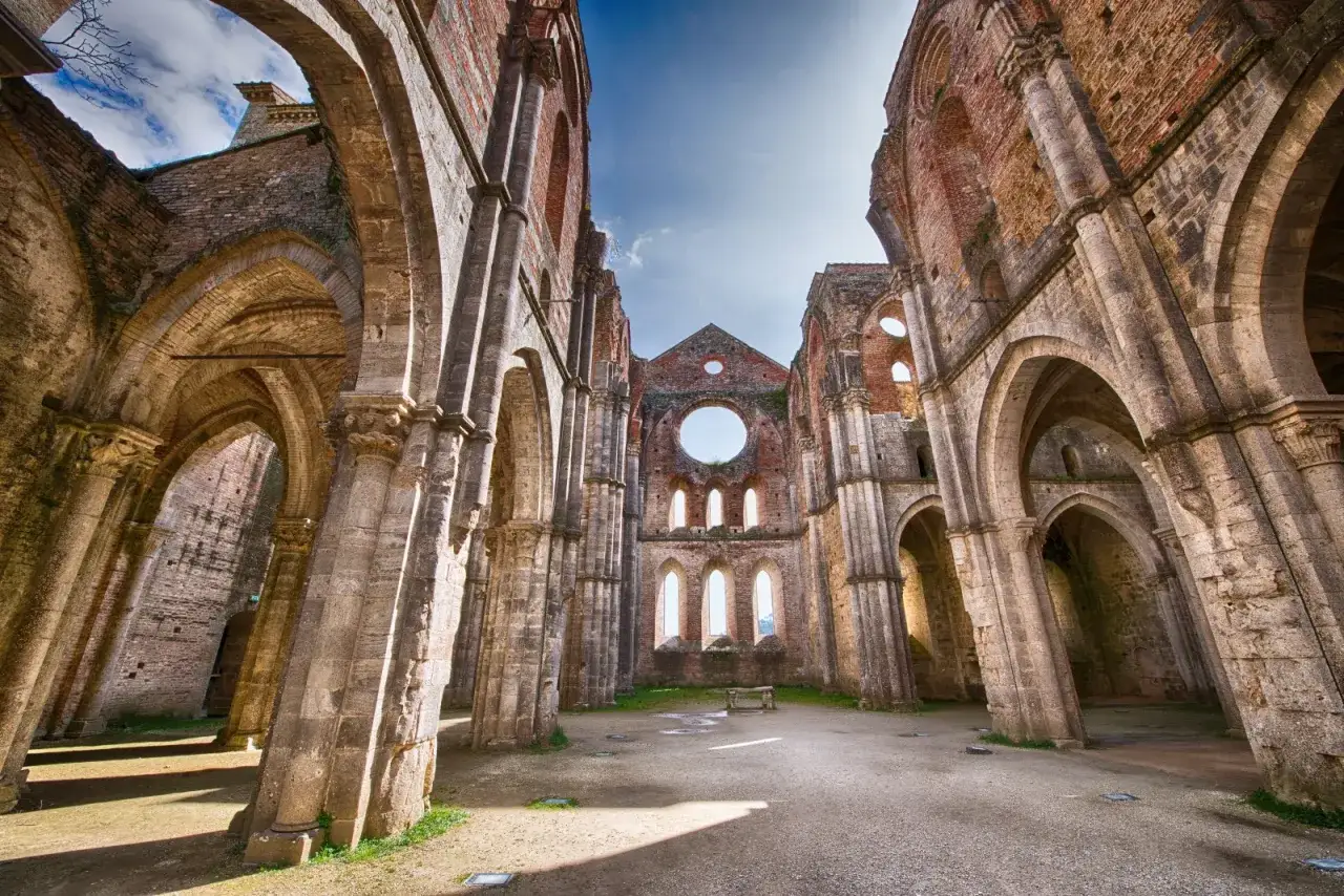 Rovine di un'abbazia con archi maestosi e un grande rosone. Qui si trova la spada nella roccia, leggenda e storia si fondono.