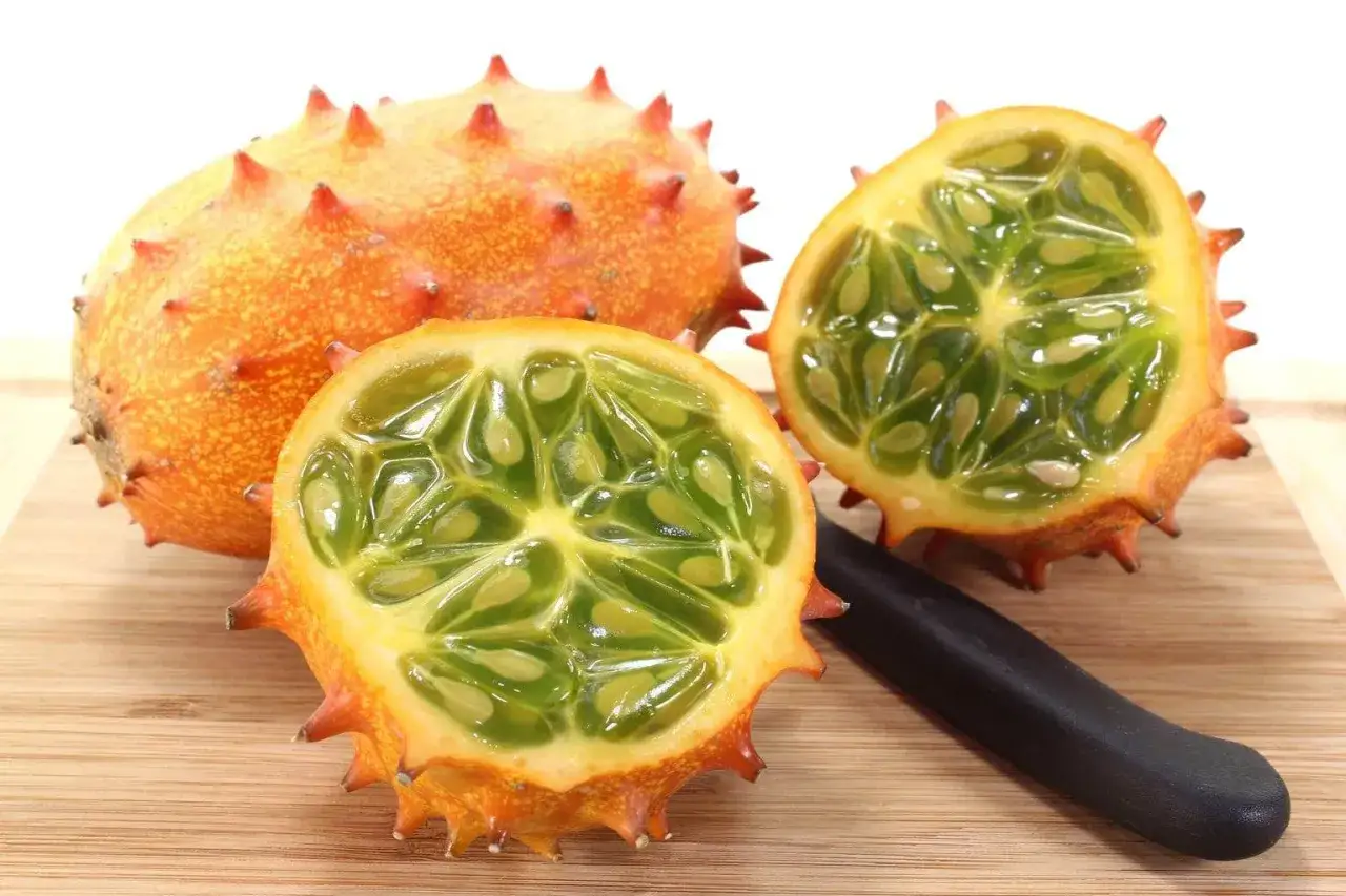 Kiwano przekrojone na pół, ukazujące zielony, galaretowaty miąższ z pestkami. Obok leży nóż, gotowy do dalszego przygotowania. Oto jak jeść kiwano!