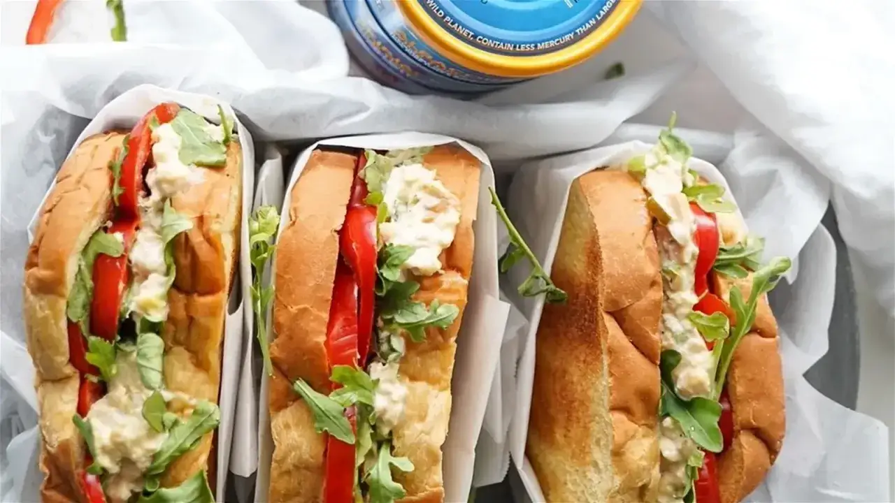Trzy kanapki z bułką, pomidorem, rukolą i kremową pastą z tuńczyka i jajka. Idealne na szybki lunch.