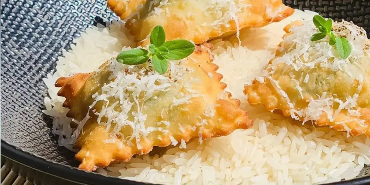 Barbajuan recette : raviolis frits dorés, garnis de fromage râpé et d'une touche de verdure, servis sur un lit de riz blanc.