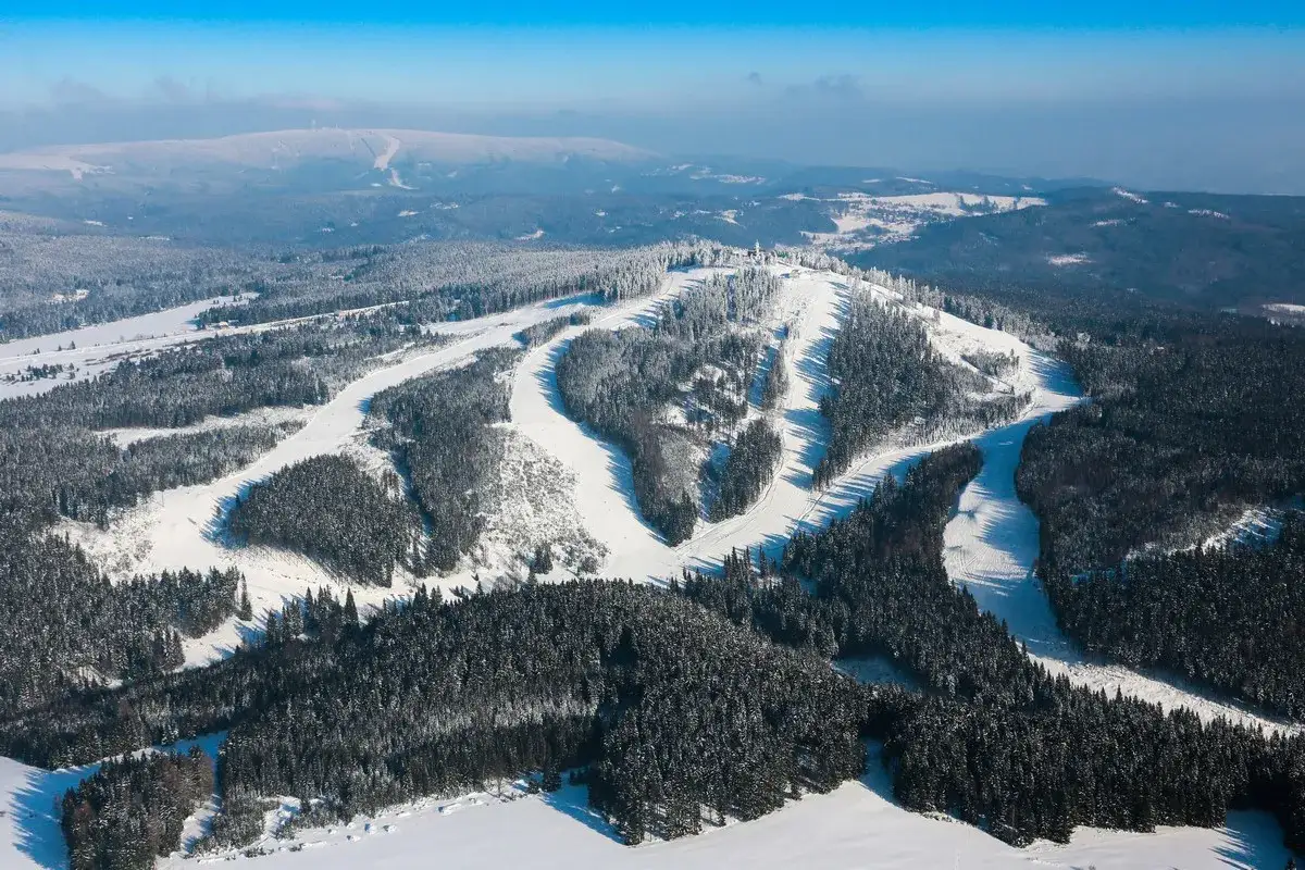 Schneebedeckte H&auml;nge und W&auml;lder, perfekt f&uuml;r Plesivec Ski. Die Pisten schl&auml;ngeln sich durch die verschneite Landschaft.