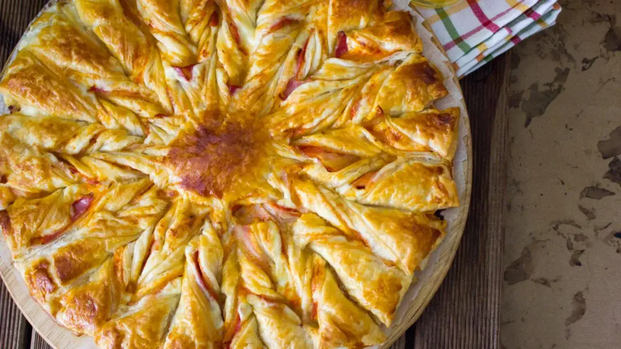 Delicioso hojaldre jamón york y queso al horno, con forma de estrella, recién salido del horno y listo para disfrutar.