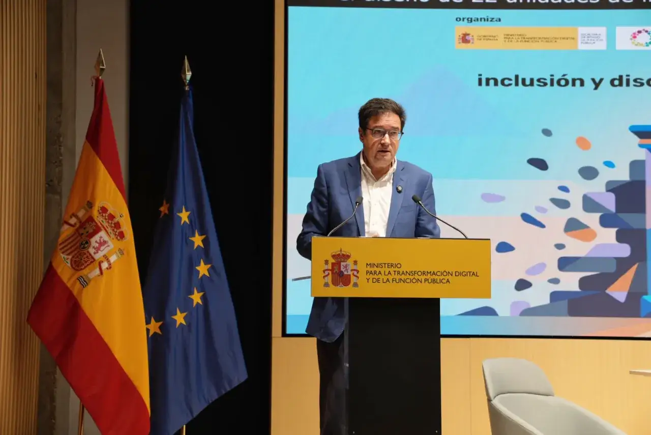 Ponente habla sobre gesti&oacute;n p&uacute;blica, con banderas de Espa&ntilde;a y UE.
