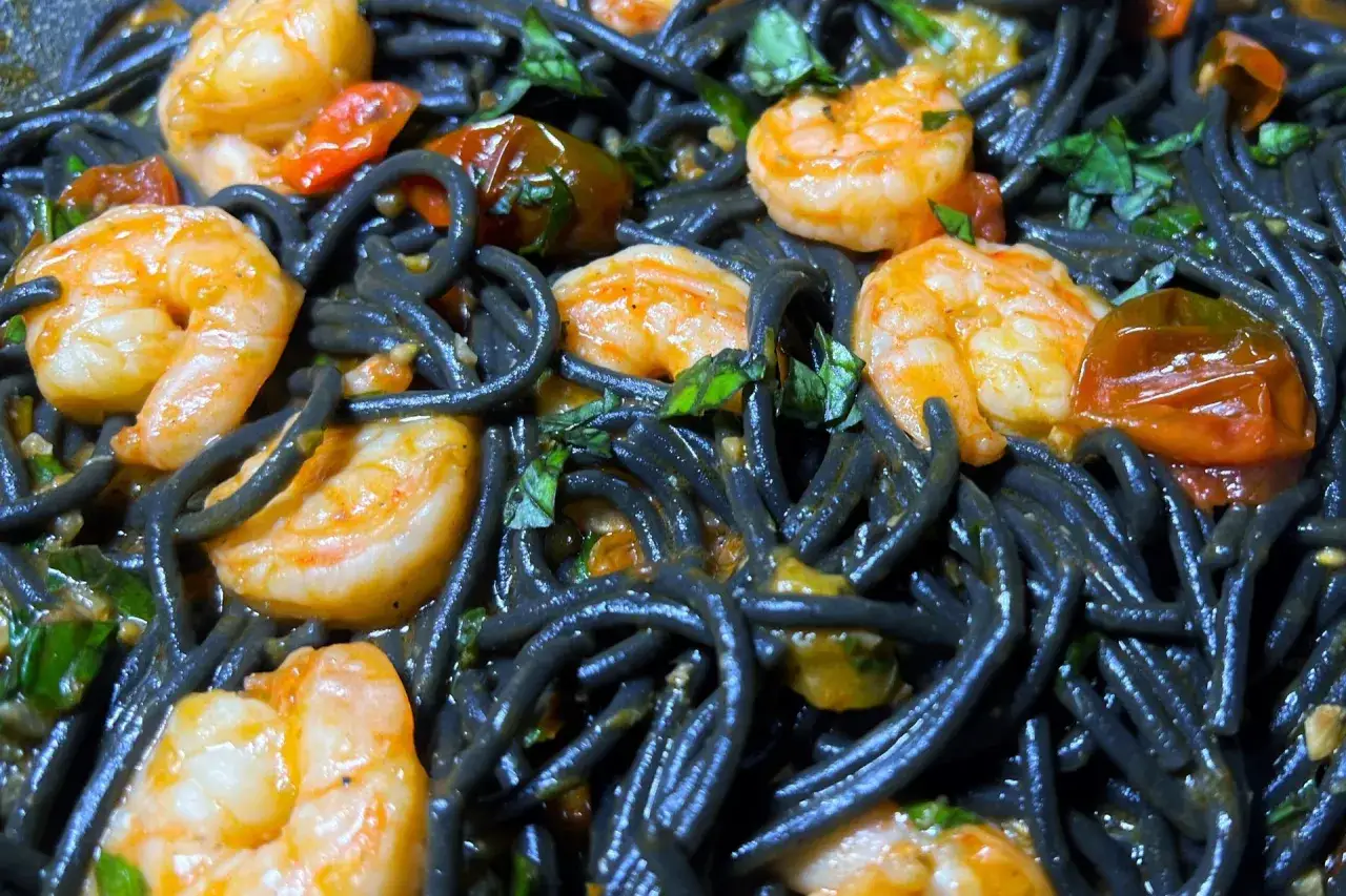 Schwarze Spaghetti mit Garnelen, Kirschtomaten und Kräutern. Ein köstliches Gericht, das die Sinne verzaubert.