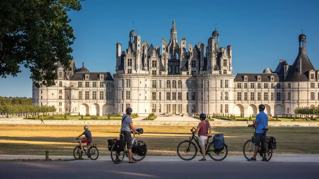 Famille &agrave; v&eacute;lo devant le majestueux **Ch&acirc;teau de Chambord**, un joyau de la Loire.