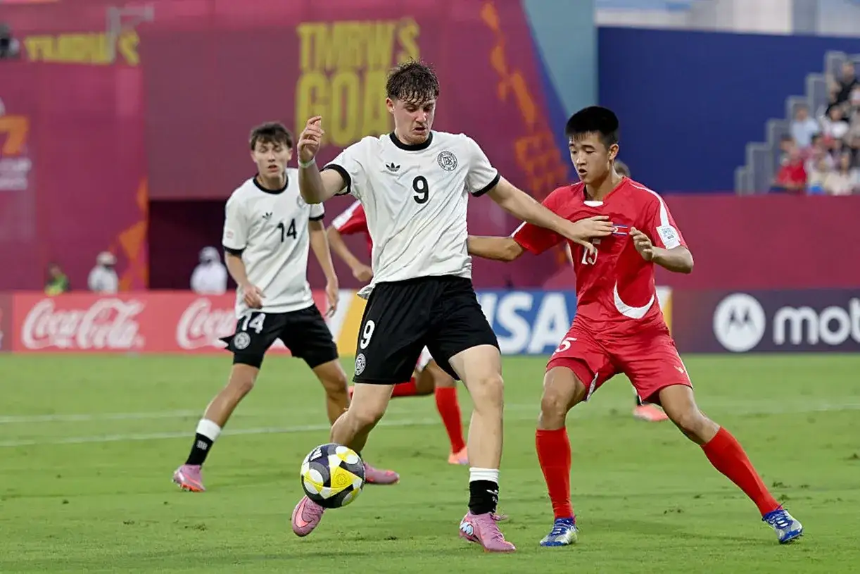 Piłkarze Niemiec i Korea Północna walczą o piłkę podczas meczu.