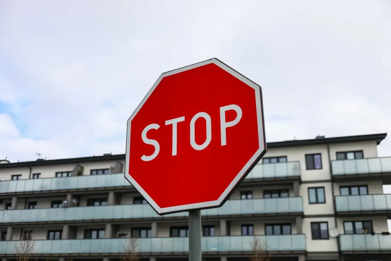 Czerwony znak stop przed nowoczesnym budynkiem mieszkalnym.