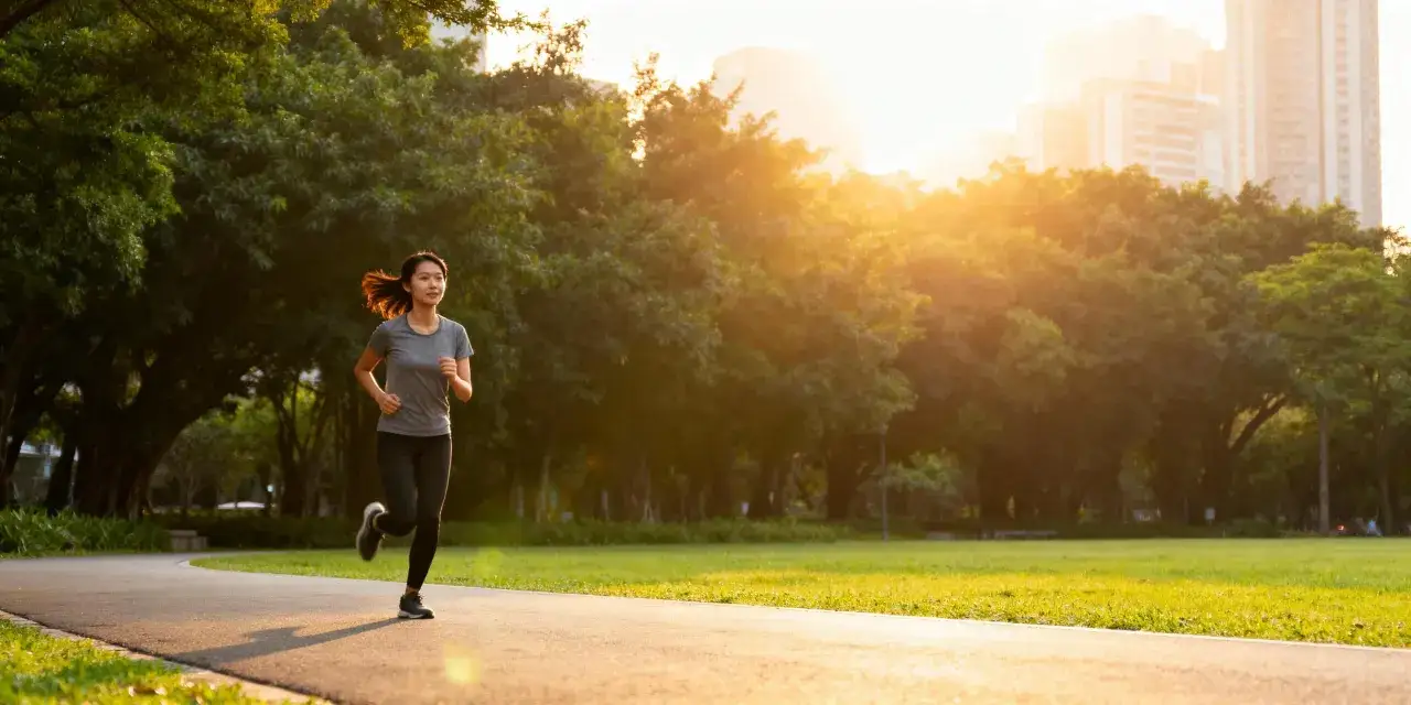 Donna corre in un parco al tramonto, godendo dei benefici della corsa per la salute e il benessere.