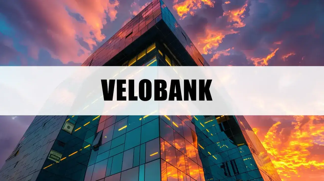 Nowoczesny budynek banku VELOBANK o szklanej fasadzie, odbijający ogniste chmury zachodzącego słońca.