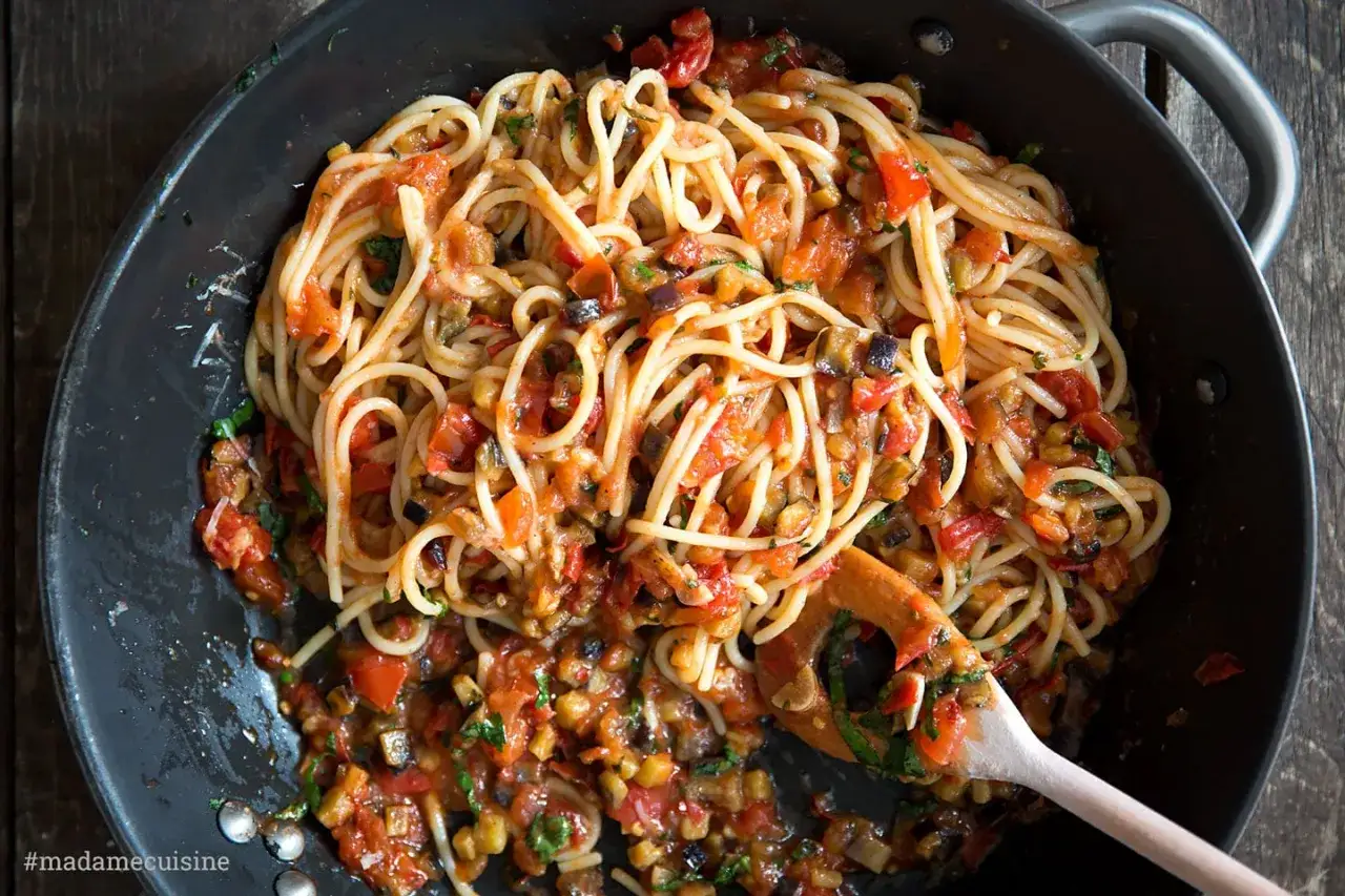 Spaghetti alla carrettiera mit Tomaten, Auberginen und Kr&auml;utern in einer Pfanne, bereit zum Servieren.