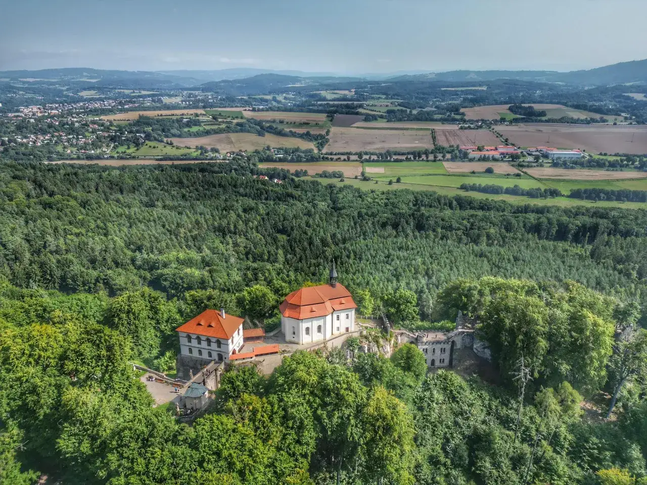 Malownicze widoki na czeskie krajobrazy, idealne na trasy rowerowe w czechach. Zamek na wzg&oacute;rzu otoczony lasem.