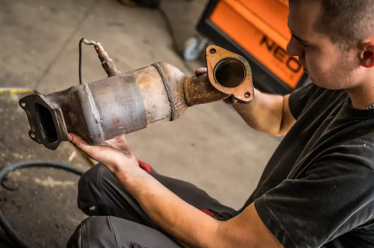 Mechanik ogląda zardzewiały element układu wydechowego, przygotowując się do czyszczenia DPF.