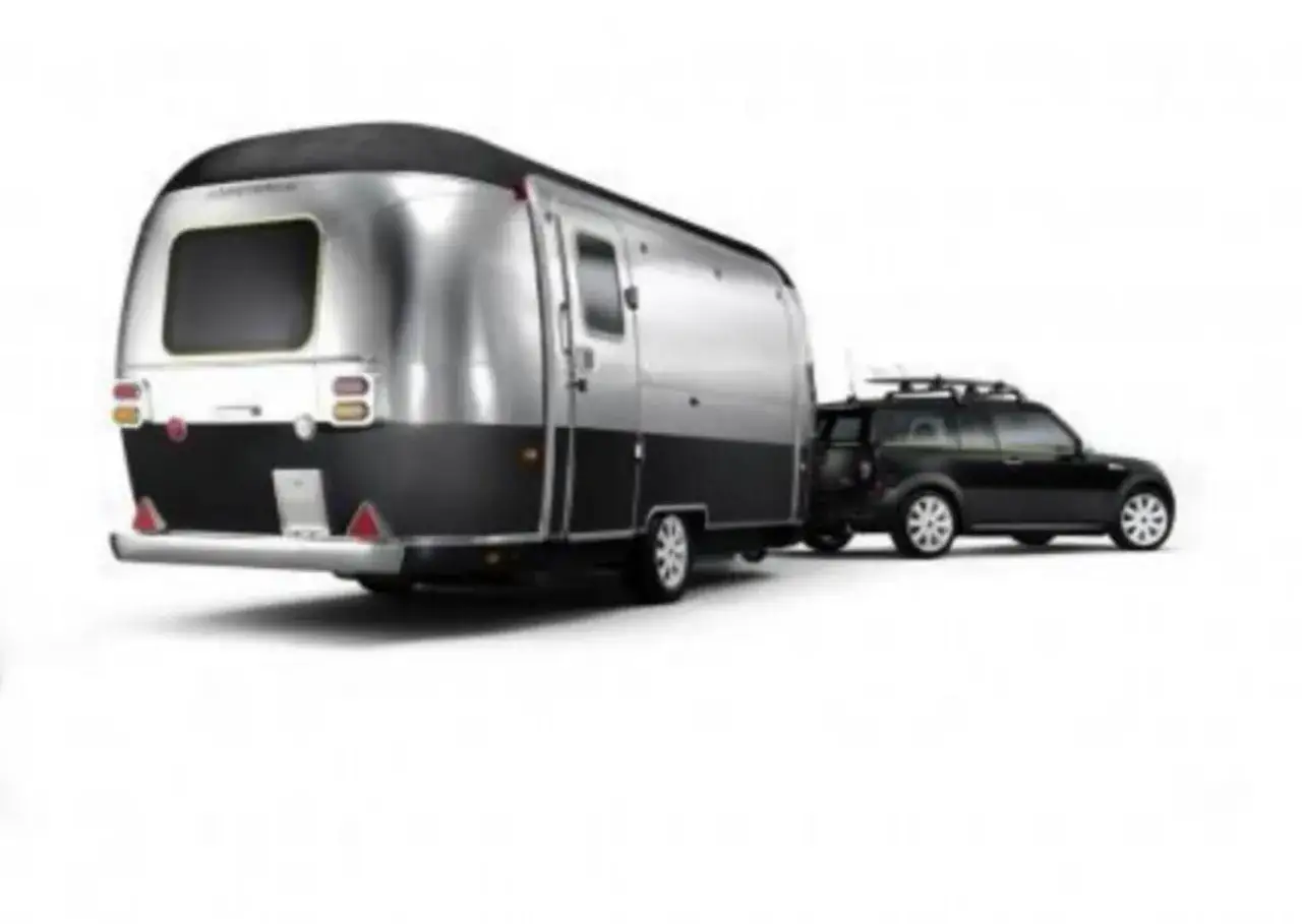 Un coche negro con portaequipajes remolca una caravana plateada y negra. Ideal para quienes tienen el carnet B96 y quieren viajar con estilo.