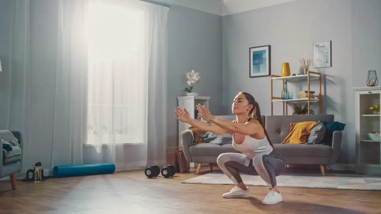 Mujer haciendo sentadillas en casa, ideal para ejercicios postparto cuando empezar.