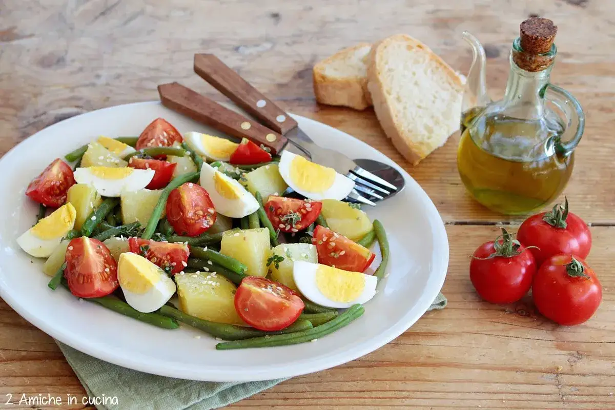 Deliziosa insalata di fagiolini con patate, pomodorini e uova sode, condita con olio d'oliva.