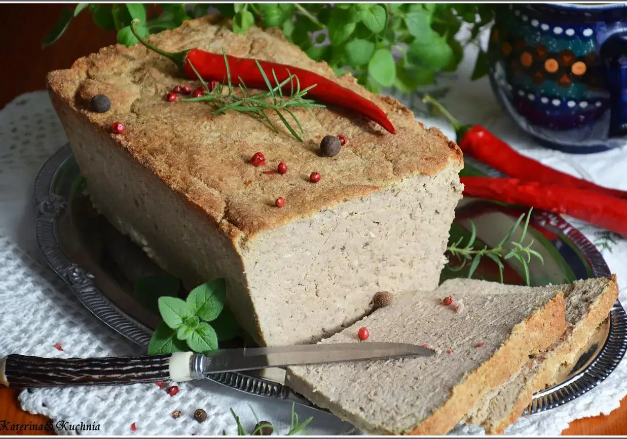 Pyszny pasztet mieszany drobiowo-wieprzowy, udekorowany papryczką chili i ziołami, gotowy do podania z chlebem.